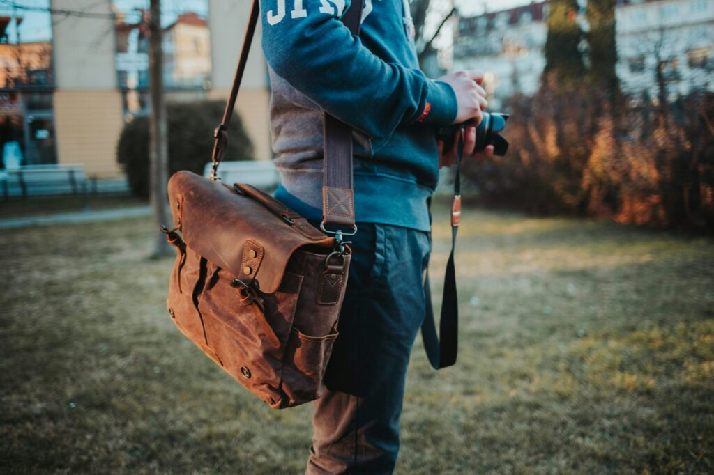 Closeup shot of a photographer holding a camera and a bag