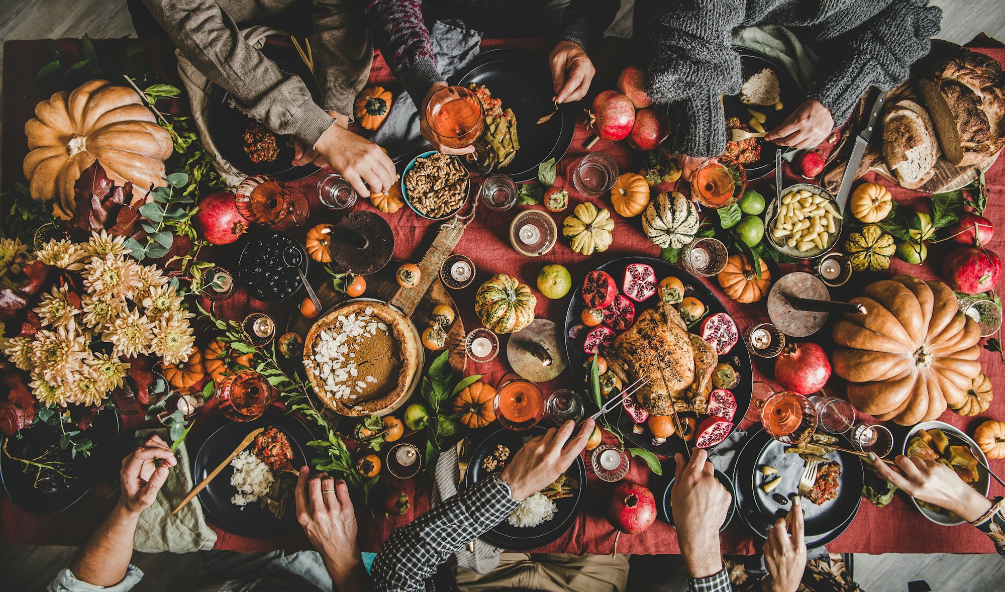 People eating and drinking wine at Thanksgiving celebration dinner table