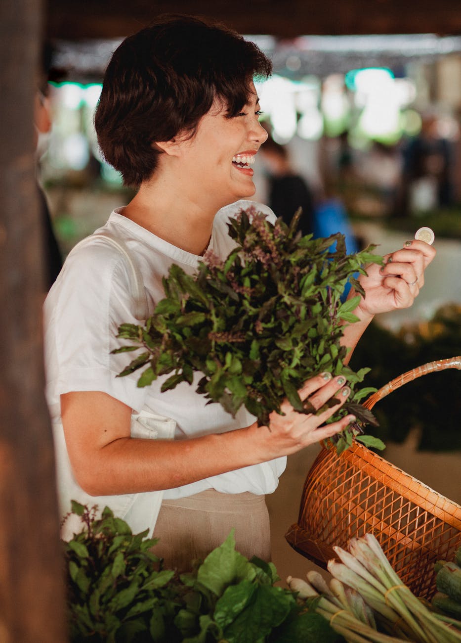 happy asian buyer with bundle of bay leaves in market